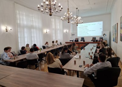 osebe sedijo na sestanku in spremljajo prezentacijo